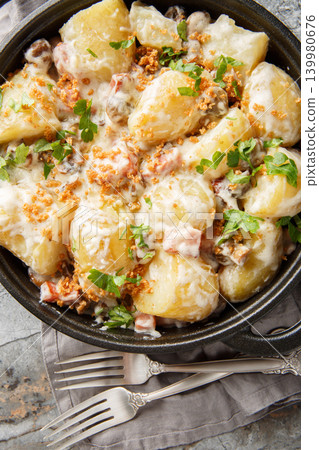 Baked potatoes in a creamy mushroom sauce with bacon sprinkled with breadcrumbs and parsley close-up in a frying pan on the table. Vertical top view Baked potatoes in a creamy mushroom sauce with bacon sprinkled with breadcrumbs and parsley close-up in a frying pan on the table. Vertical top view 139980676