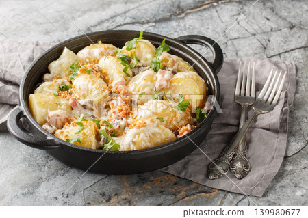 Delicious young potatoes in a creamy mushroom sauce with bacon sprinkled with breadcrumbs and parsley close-up in a frying pan. Horizontal Delicious young potatoes in a creamy mushroom sauce with bacon sprinkled with breadcrumbs and parsley close-up in a frying pan. Horizontal 139980677