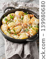 Homemade new potatoes with creamy mushroom sauce, bacon, and breadcrumbs, close-up, in a frying pan. Vertical 139980680