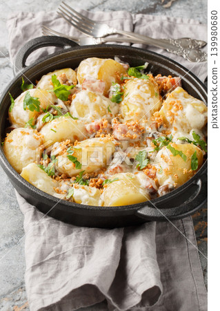 Homemade new potatoes with creamy mushroom sauce, bacon, and breadcrumbs, close-up, in a frying pan. Vertical Homemade new potatoes with creamy mushroom sauce, bacon, and breadcrumbs, close-up, in a frying pan. Vertical 139980680