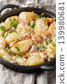 Boiled new potatoes with creamy mushroom sauce and bacon close-up in a frying pan. Vertical 139980681