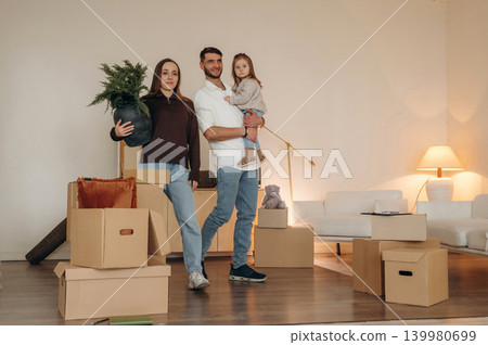 The young family with child and dog moving into new home, standing among cardboard boxes The young family with child and dog moving into new home, standing among cardboard boxes 139980699