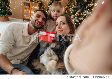 Selfie time, smiling. Happy family with child and dog celebrating Christmas together at home with decorated tree Selfie time, smiling. Happy family with child and dog celebrating Christmas together at home with decorated tree 139980744