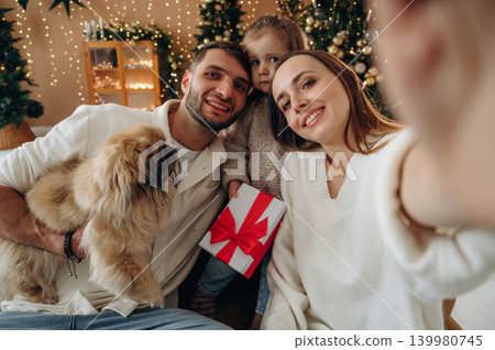 Selfie time, smiling. Happy family with child and dog celebrating Christmas together at home with decorated tree Selfie time, smiling. Happy family with child and dog celebrating Christmas together at home with decorated tree 139980745