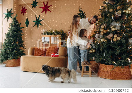 Happy family with child and dog celebrating Christmas together at home with decorated tree 139980752