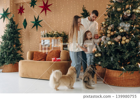 By the decorated tree. Happy family with child and dog celebrating Christmas together at home By the decorated tree. Happy family with child and dog celebrating Christmas together at home 139980755