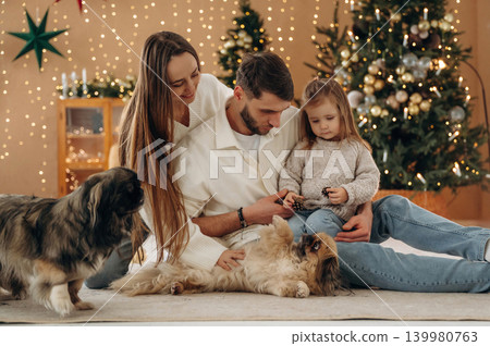 Bonding, having great time. Happy family with child and dog celebrating Christmas together at home with decorated tree Bonding, having great time. Happy family with child and dog celebrating Christmas together at home with decorated tree 139980763