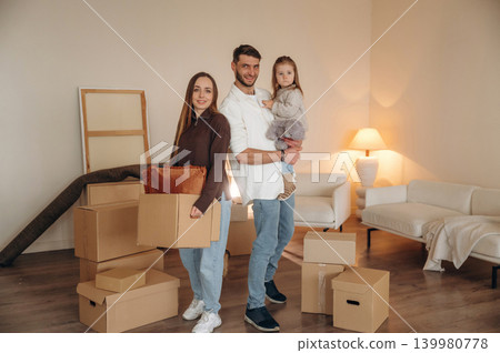 Among cardboard boxes. Happy young family with child and dog moving into new home Among cardboard boxes. Happy young family with child and dog moving into new home 139980778