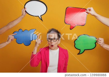 Woman in pink blazer is expressing excitement while surrounded by colorful speech bubbles, showcasing communication and engagement in a vibrant setting Woman in pink blazer is expressing excitement while surrounded by colorful speech bubbles, showcasing communication and engagement in a vibrant setting 139980866