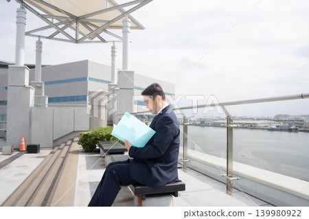 一位商人正在屋頂上查看文件。 一位商人正在屋頂上查看文件。 139980922