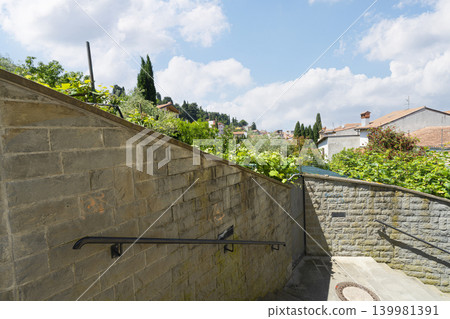 A stone staircase with handrails leads up towards a hillside town with red-tiled roofs in Piran, Slovenia A stone staircase with handrails leads up towards a hillside town with red-tiled roofs in Piran, Slovenia 139981391