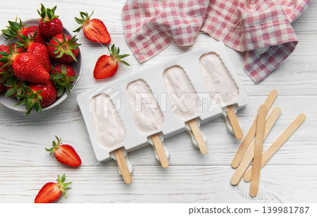 Strawberry popsicles in making process on white wooden surface Strawberry popsicles in making process on white wooden surface 139981787