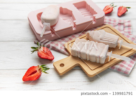 Making homemade strawberry ice pops with silicone mold Making homemade strawberry ice pops with silicone mold 139981791