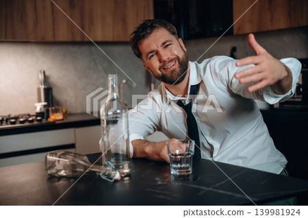 Man in a white shirt and tie is sitting at a kitchen table with a glass of whiskey, showcasing a relaxed atmosphere and the concept of enjoying alcoholic beverages Man in a white shirt and tie is sitting at a kitchen table with a glass of whiskey, showcasing a relaxed atmosphere and the concept of enjoying alcoholic beverages 139981924