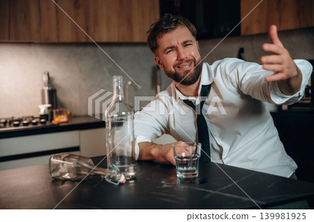 Smiling man in a white shirt and black tie gestures while sitting at a kitchen table with an empty bottle and glass, conveying a relaxed atmosphere and social interaction Smiling man in a white shirt and black tie gestures while sitting at a kitchen table with an empty bottle and glass, conveying a relaxed atmosphere and social interaction 139981925