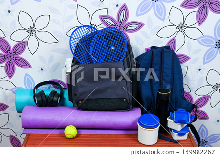 sports backpacks with rackets fitness mats and accessories on a table 139982267