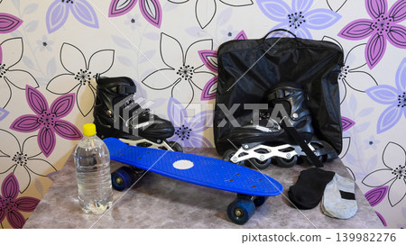 roller skates skateboard water bottle and socks on a table near a wall roller skates skateboard water bottle and socks on a table near a wall 139982276