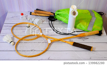two wooden rackets and shuttlecocks with a jump rope and a green backpack on a light floor 139982280