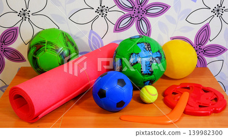 colorful sports balls and a fitness mat on a wooden table 139982300