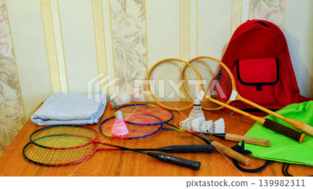 badminton rackets and shuttlecocks on a wooden table next to a red backpack badminton rackets and shuttlecocks on a wooden table next to a red backpack 139982311