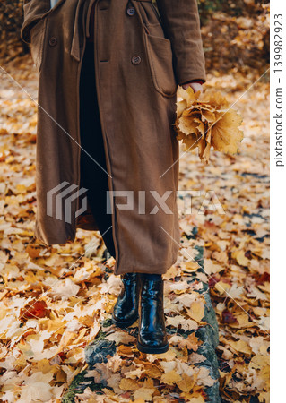 Person stands outdoors on ground holding bouquet of autumn foliage. Silent walking autumn, natural ASMR, Sensory Immersion, Mental Clarity. Person stands outdoors on ground holding bouquet of autumn foliage. Silent walking autumn, natural ASMR, Sensory Immersion, Mental Clarity. 139982923