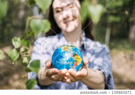 Person holds small globe in hands while standing in forest. Corporate social responsibility, ESG strategy visual, environmental protection goals. Person holds small globe in hands while standing in forest. Corporate social responsibility, ESG strategy visual, environmental protection goals. 139983071