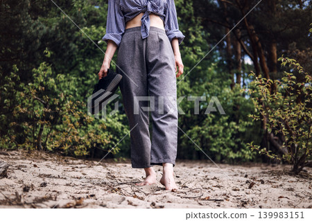Bare feet of person walk across sandy ground while holding shoes. Digital detox lifestyle, mindfulness walking meditation, healing power of earth. Bare feet of person walk across sandy ground while holding shoes. Digital detox lifestyle, mindfulness walking meditation, healing power of earth. 139983151