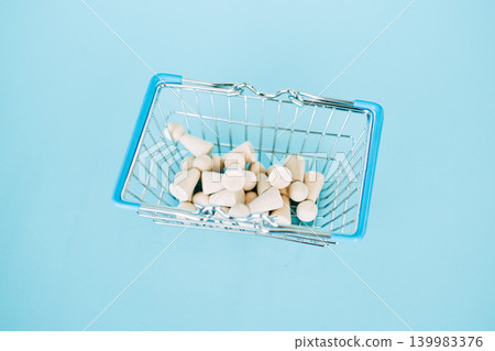 Wooden peg dolls lie inside miniature wire shopping basket against blue background. Talent acquisition strategy, recruitment process outsourcing, human resources management, Hiring spree trends. Wooden peg dolls lie inside miniature wire shopping basket against blue background. Talent acquisition strategy, recruitment process outsourcing, human resources management, Hiring spree trends. 139983376