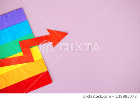 Red upward arrow lies on rainbow flag against purple background. Pink economy growth, LGBTQ market trends, queer spending power, inclusive business expansion. Red upward arrow lies on rainbow flag against purple background. Pink economy growth, LGBTQ market trends, queer spending power, inclusive business expansion. 139983378