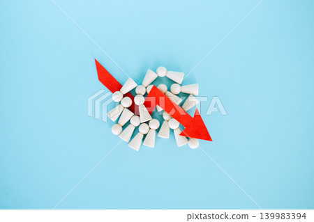 Red downward arrow lies on pile of wooden peg dolls over blue background. Mass layoffs 2026, workforce reduction impact, global unemployment surge, Economic recession. Red downward arrow lies on pile of wooden peg dolls over blue background. Mass layoffs 2026, workforce reduction impact, global unemployment surge, Economic recession. 139983394