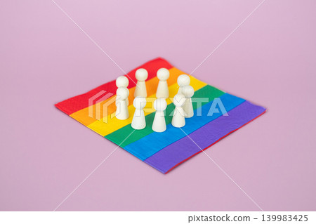 Wooden figurines arranged in circular formation on rainbow pride flag. LGBTQ rights advocacy, social justice movement, human rights protection. Wooden figurines arranged in circular formation on rainbow pride flag. LGBTQ rights advocacy, social justice movement, human rights protection. 139983425