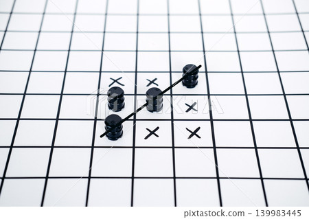 Small black barrels and hand drawn marks on grid surface with strike through line. Oil trade blockade, diplomatic standoff issues, strategic energy flashpoints. Small black barrels and hand drawn marks on grid surface with strike through line. Oil trade blockade, diplomatic standoff issues, strategic energy flashpoints. 139983445