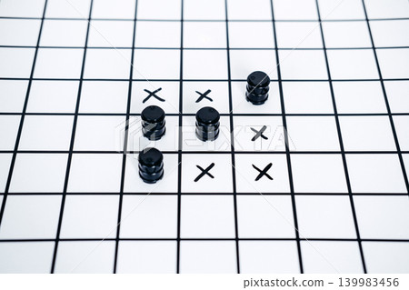 Black miniature barrels and crosses placed on grid in style of tic tac toe game. Persian Gulf crisis, Strait of Hormuz security, Middle East oil conflict. Black miniature barrels and crosses placed on grid in style of tic tac toe game. Persian Gulf crisis, Strait of Hormuz security, Middle East oil conflict. 139983456