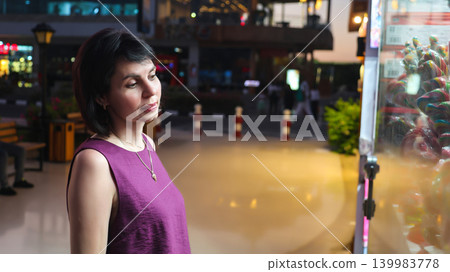 An adult woman near a store window late in the evening 139983778