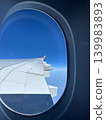 The view of the airplane wing through the porthole 139983893