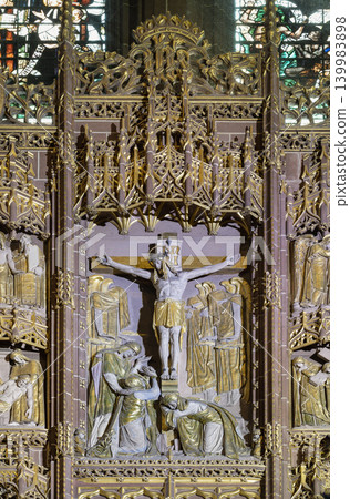 As an extraordinary masterpiece of Gothic Revival craftsmanship, the High Altar reredos of Liverpool Cathedral frames a central sacred scene. The structure is flanked by intricate vertical columns 139983898