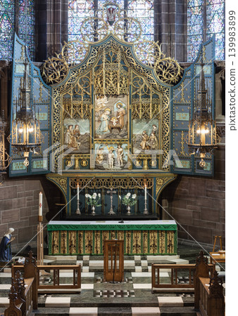 A magnificent gilded triptych reredos rises gracefully above the high altar of the Lady Chapel within the Anglican Liverpool Cathedral, its ornate openwork tracery gleaming with gold under the soft A magnificent gilded triptych reredos rises gracefully above the high altar of the Lady Chapel within the Anglican Liverpool Cathedral, its ornate openwork tracery gleaming with gold under the soft 139983899
