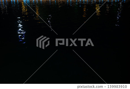 Colorful light reflections on water ripples at night, abstract neon background with copy space. 139983910