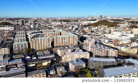 An aerial view of the city, capturing a clear blue sky and densely packed residential areas. An aerial view of the city, capturing a clear blue sky and densely packed residential areas. 139983955