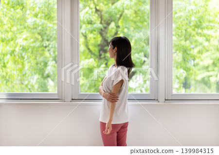 The back view of a woman stretching by the window. The back view of a woman stretching by the window. 139984315