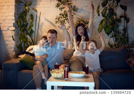 Family cheering during home movie night with popcorn and juice. 139984720