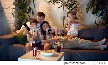Cozy family movie night with kids eating popcorn on couch. 139984721