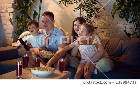 Family movie night with children pointing at screen in living room. Family movie night with children pointing at screen in living room. 139984731
