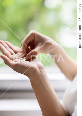 Close-up of a woman's fingers picking up a pill from her palm. Close-up of a woman's fingers picking up a pill from her palm. 139984745