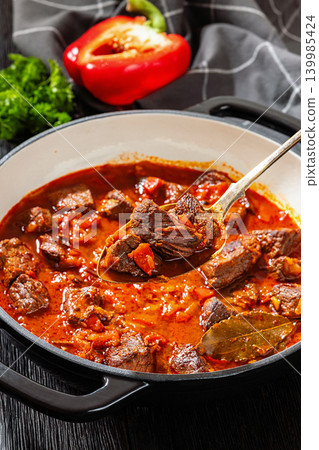 Spoon picking beef chunk from goulash stew Spoon picking beef chunk from goulash stew 139985424
