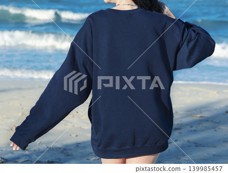 Blank dark blue oversized unisex sweatshirt mockup on young woman on the beach, back copy space Blank dark blue oversized unisex sweatshirt mockup on young woman on the beach, back copy space 139985457