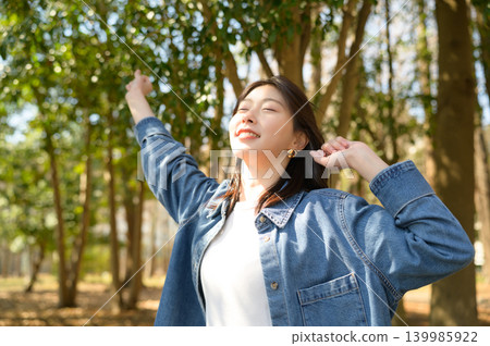 Japanese woman stretches and refreshes herself in a park. 139985922