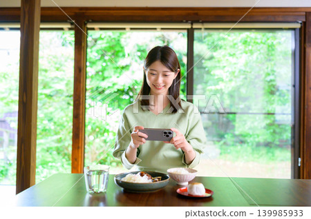 Japanese woman taking a photo of her meal with her smartphone Japanese woman taking a photo of her meal with her smartphone 139985933