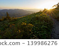 The mountain trail along the ridgeline is bathed in the setting sun. 139986276