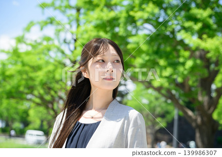 A Japanese woman looks up at the fresh green leaves. A Japanese woman looks up at the fresh green leaves. 139986307